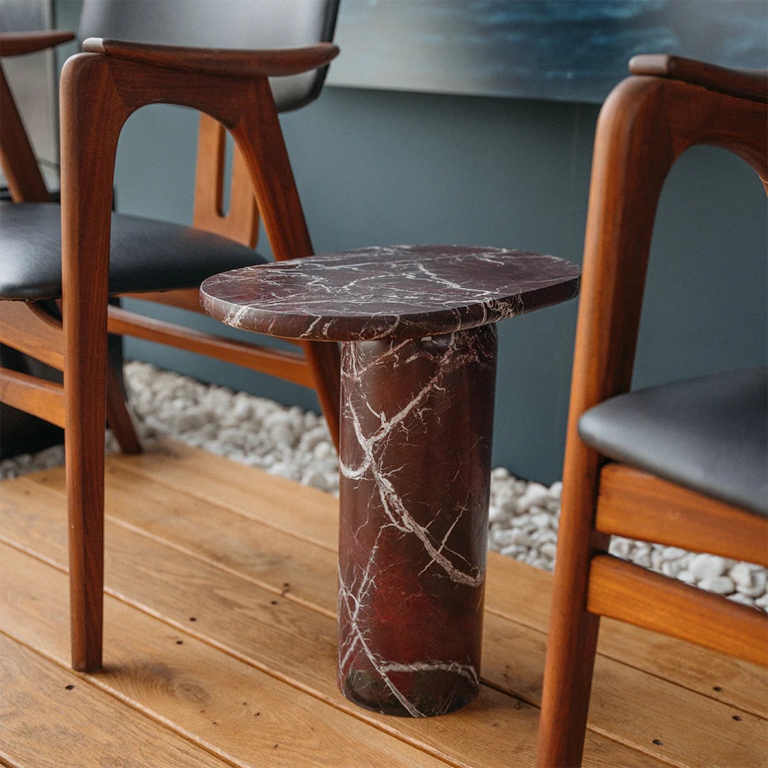 Burgundy marble cylindrical side table between wooden chairs - stylish accent piece for seating area